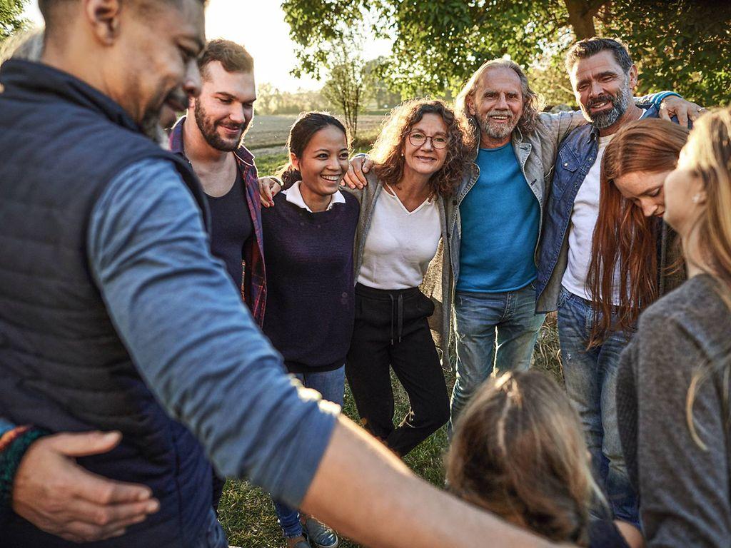 Bild: Menschen unterschiedlichen Alters umarmen sich draußen.