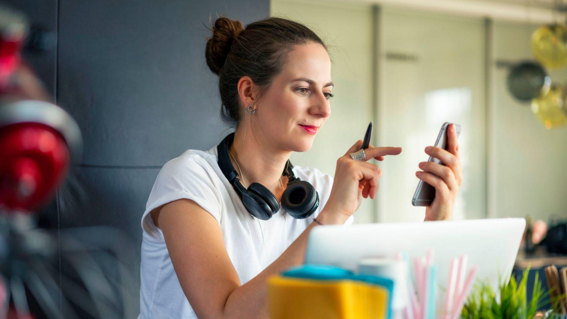 Bild: Junge Frau schaut auf ihr Handy und tippt auf den Screen.