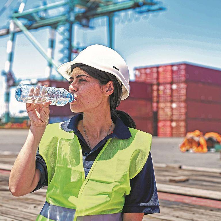 Symbolbild Hitze: Arbeiterin im Hafen trinkt eine Flasche Wasser