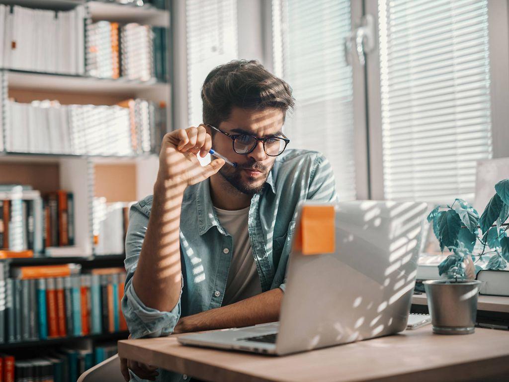 Bild: Mann sitzt vor Laptop und hat Stift im Mund