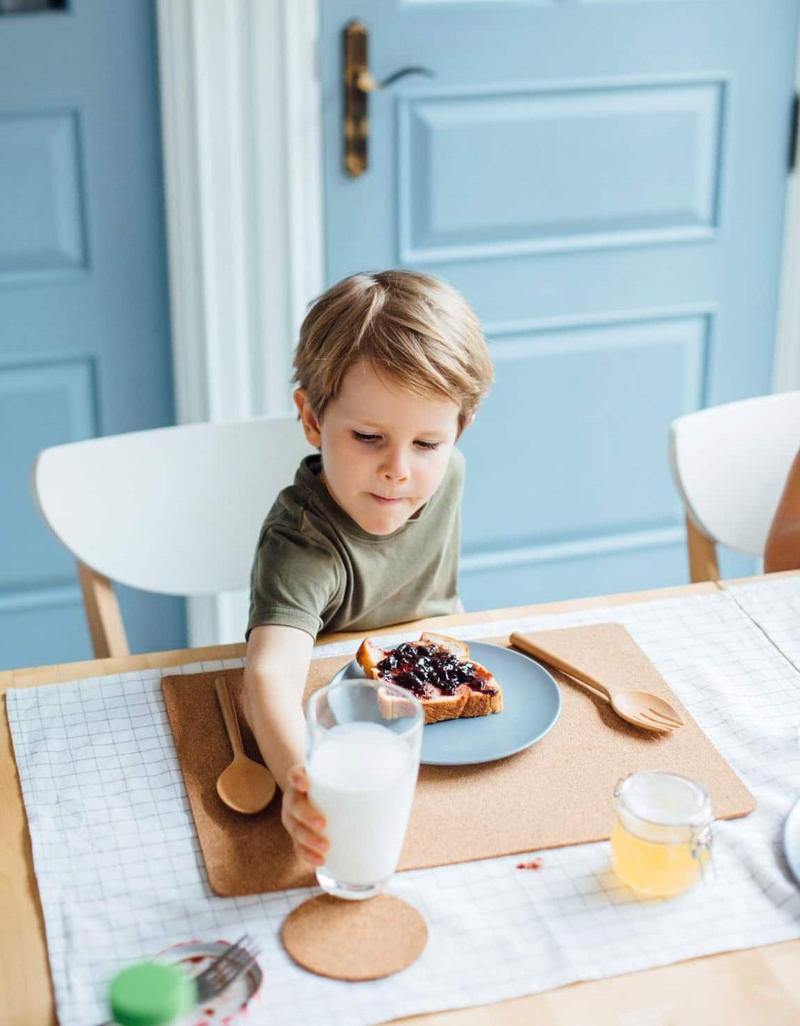 DMP Diabetes bei Kindern: Kleiner Junge greift nach einem Glas Milch.