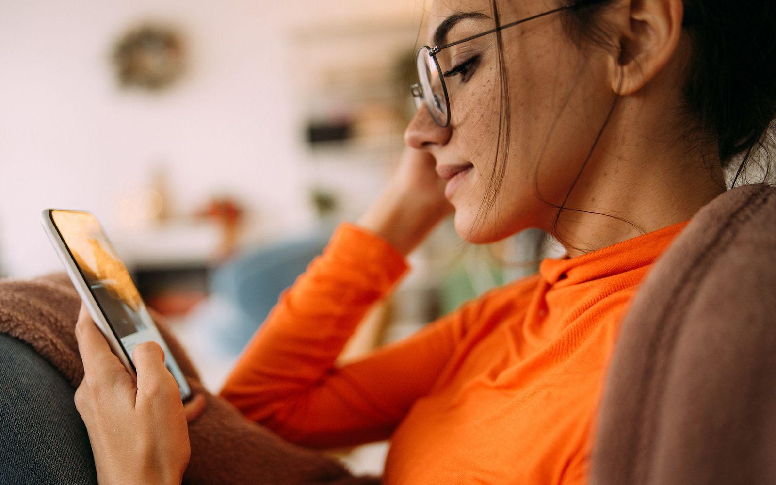 Bild: Junge Frau mit Brille schaut auf Ihr Smartphone