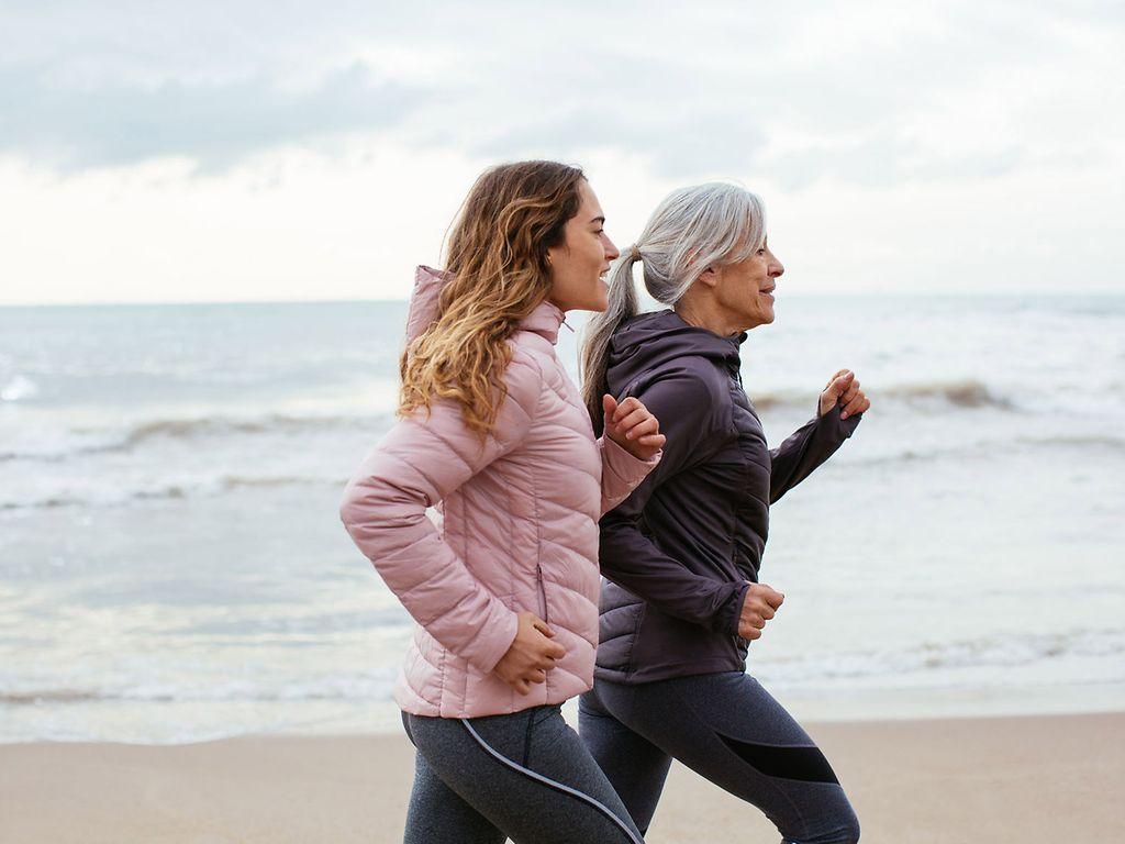 Ausdauertraining: Zwei Frauen joggen am Strand.